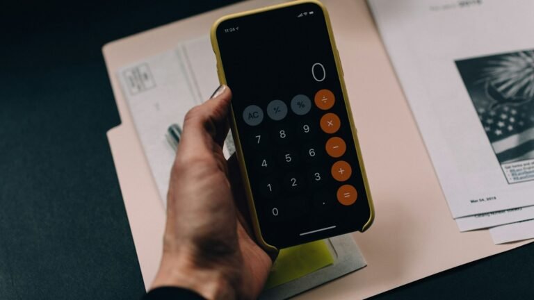 Smartphone affichant une calculatrice au-dessus d'un dossier de comptes