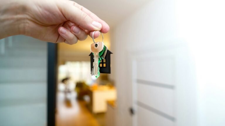 Clés d'un logement tenues devant la porte d'entrée